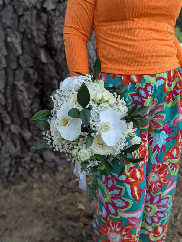 Round bridal bouquet with white orchids, cream roses, and gypsophila, sophisticated country style.
