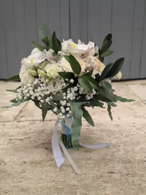 Romantic organic bridal bouquet with white orchids, cream roses, gypsophila, and green foliage.
