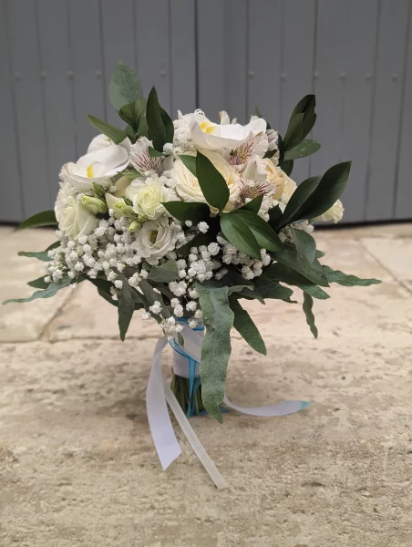 Romantic organic bridal bouquet with white orchids, cream roses, gypsophila, and green foliage.