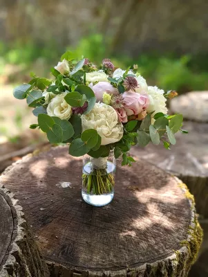 Bouquet de mariée champêtre avec pivoines crème, roses pâles, eucalyptus et fleurs bordeaux. Idéal pour un mariage d'été.