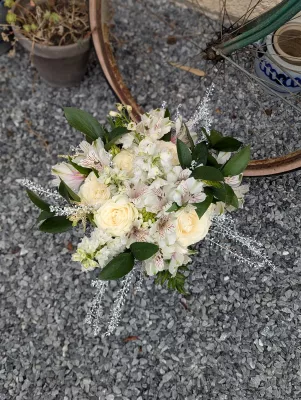 Bouquet de mariée classique avec roses ivoire, alstroemerias blancs et feuillage vert pour un mariage d'été élégant.