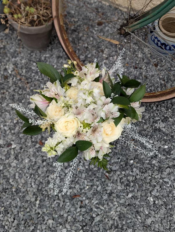 Bouquet de mariée classique avec roses ivoire, alstroemerias blancs et feuillage vert pour un mariage d'été élégant.