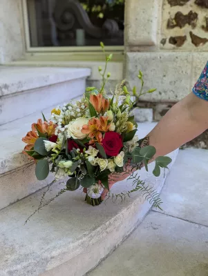 Romantic organic bridal bouquet with red roses, orange alstroemerias and eucalyptus for a wedding.