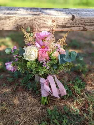 Bouquet de mariée champêtre avec roses blanches, roses claires, cosmos fuchsia, eucalyptus et astilbe.