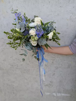 Élégant bouquet de mariée bohème pour le mariage de Salomé, composé de roses blanches, delphiniums bleus et eucalyptus.