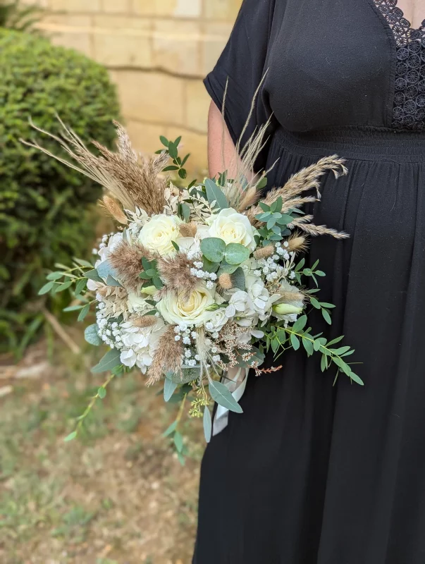 A generous bohemian bridal bouquet featuring white roses, hydrangeas, eucalyptus, and pampas grass, perfect for summer.