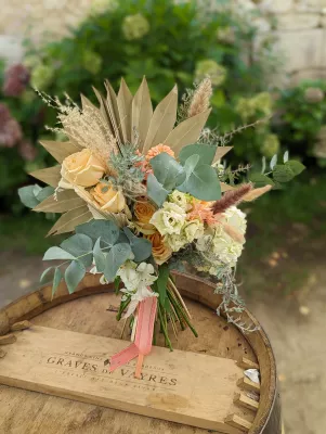 Bouquet de mariée bohème avec roses pêche, lisianthus crème, eucalyptus et palmier séché pour le mariage de Morgane à Vayres.