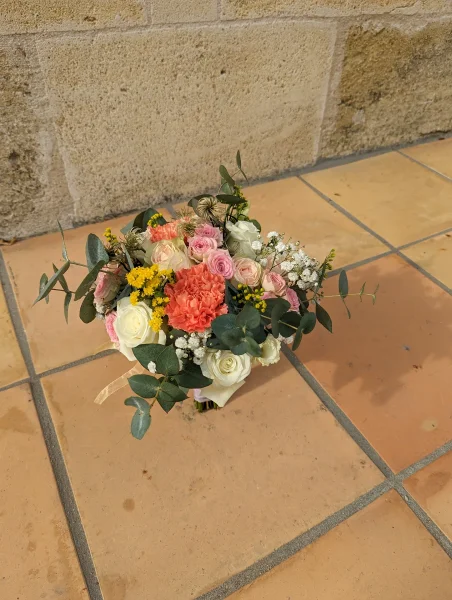 Bouquet de mariée champêtre avec roses pastel, œillets corail, eucalyptus et gypsophile pour un mariage d'été à Tabanac.