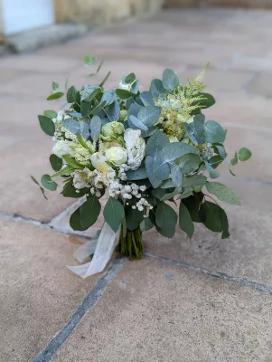 Bouquet de mariée champêtre et élégant avec des roses blanches, de l'eucalyptus et du gypsophile.