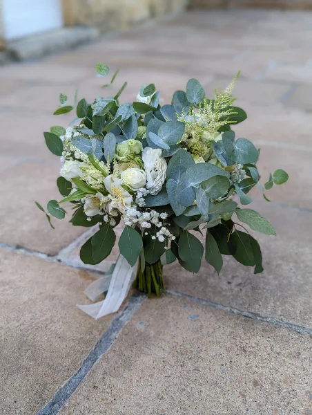 Bouquet de mariée champêtre et élégant avec des roses blanches, de l'eucalyptus et du gypsophile.