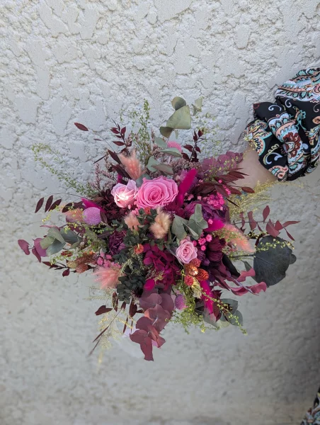 Bouquet de mariée champêtre sophistiqué avec roses fuchsia, feuillage d'eucalyptus et touches de pampa pour un mariage printanier.