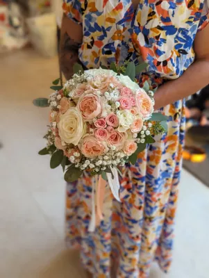 Bouquet de mariee rond et elegant avec roses creme, roses peches, gypsophile et feuillage eucalyptus pour mariage.