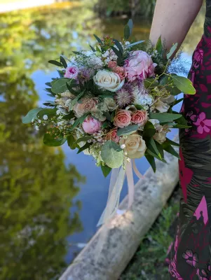 Bouquet de mariée romantique organique avec roses roses et crème, eucalyptus et feuillages verts pour un mariage.