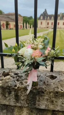 Bouquet de mariée romantique organique avec roses, lisianthus et eucalyptus, devant un château.