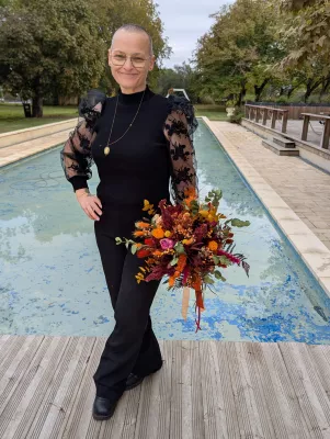 Sophisticated rustic bridal bouquet in autumn colours, held by the bride in front of a pool.