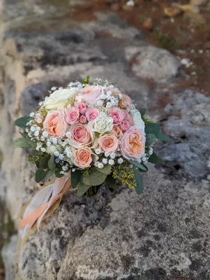 Bouquet de mariée romantique compose de roses blanches, roses peches, gypsophile et feuillage vert frais pour Leïla.