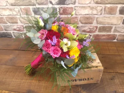 Magnifique bouquet de mariée champêtre, composé de roses colorées, lisianthus et feuillage d'eucalyptus, avec une poignée rubanée pour un mariage de printemps.
