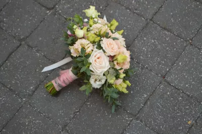 Bouquet de mariée de style bohème avec des roses poudrées, lisianthus verts et jaunes, eucalyptus et ruban rose.