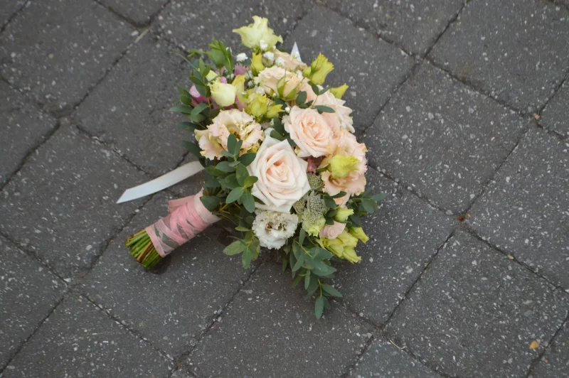 Bohemian style bridal bouquet with dusty pink roses, green and yellow lisianthus, eucalyptus and pink ribbon.