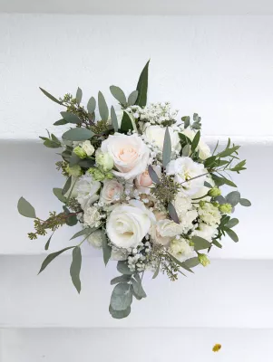 Sophisticated country-style bridal bouquet with white and pale pink roses, lisianthus, and eucalyptus.