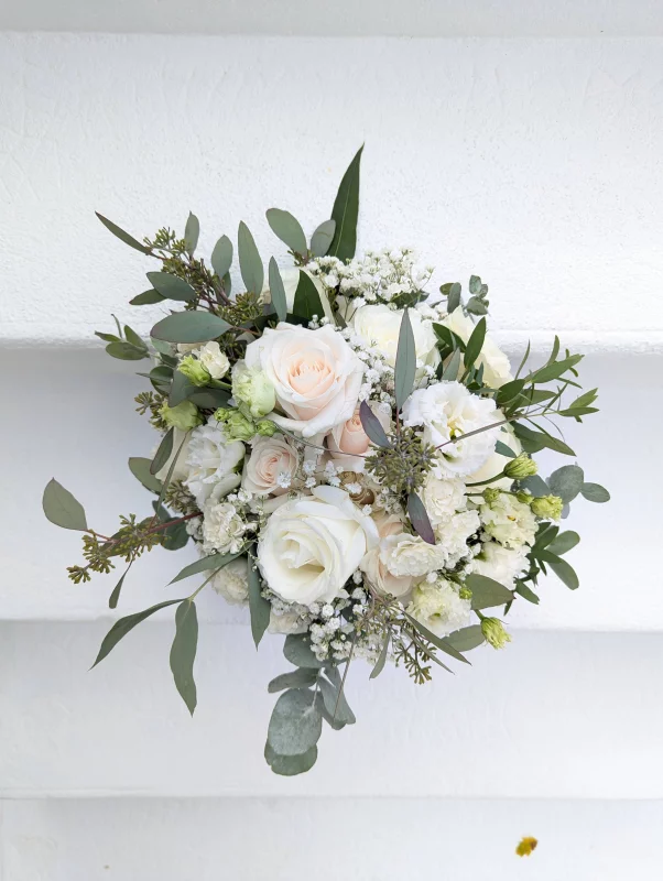 Sophisticated country-style bridal bouquet with white and pale pink roses, lisianthus, and eucalyptus.