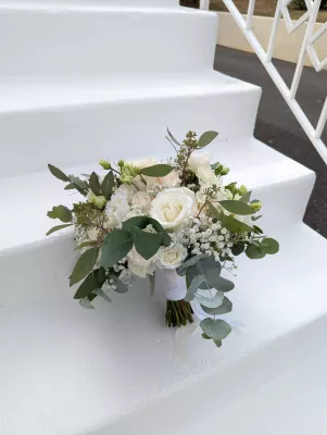 Sophisticated country-style bridal bouquet with white and pale pink roses, lisianthus, and eucalyptus.