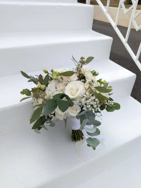 Sophisticated country-style bridal bouquet with white and pale pink roses, lisianthus, and eucalyptus.