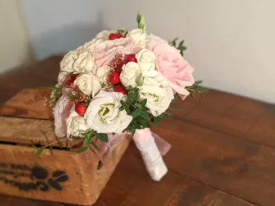 Bouquet de mariée classique avec des roses rose pâle et des lisianthus blancs, agrémenté de baies rouges pour un mariage d'automne.