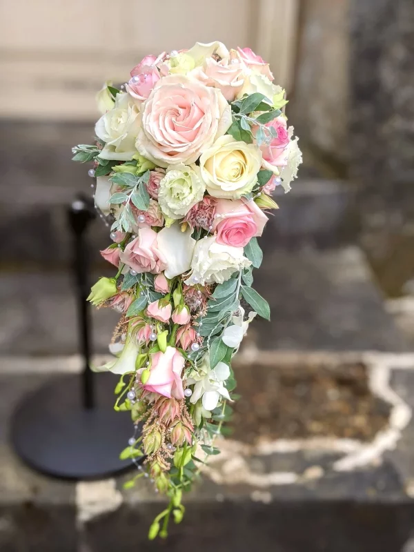 Magnificent cascading bridal bouquet featuring assorted roses, lisianthus and white callas, adorned with fine pearls and foliage.