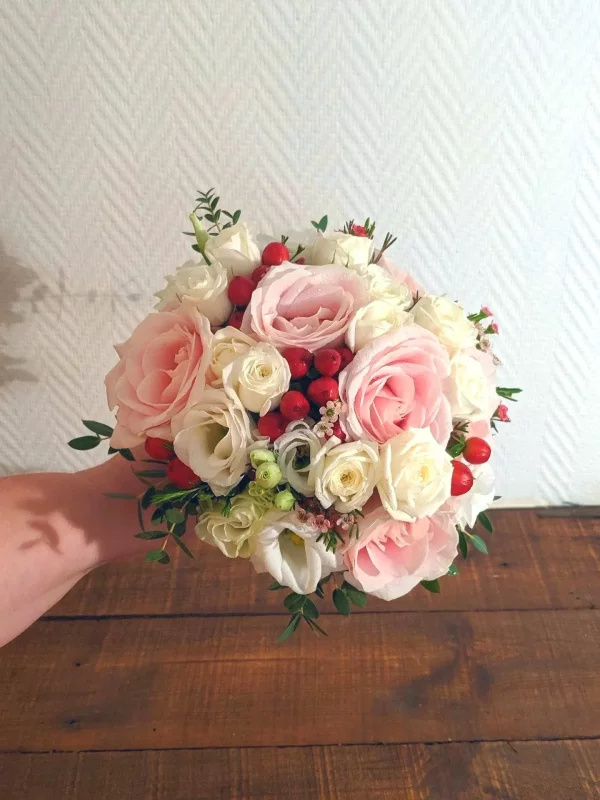 Bridal bouquet, romantic and classic, composed of pink roses and white lisianthus, with accents of red berries.