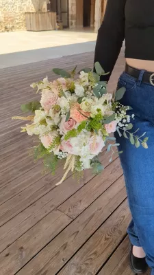 Organic romantic bridal bouquet with roses, lisianthus, and green foliage, held by the bride.