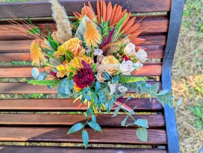 Grand bouquet de mariée bohème avec roses orange, œillet bordeaux, alstroemerias et herbe de la pampa.
