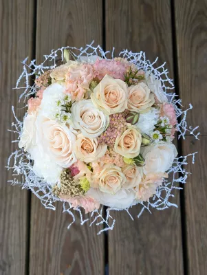 Vue de dessus d'un bouquet de mariée classique et généreux, avec roses, œillets pastel et feuillage argenté.