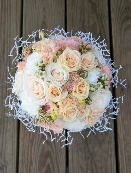 Vue de dessus d'un bouquet de mariée classique et généreux, avec roses, œillets pastel et feuillage argenté.