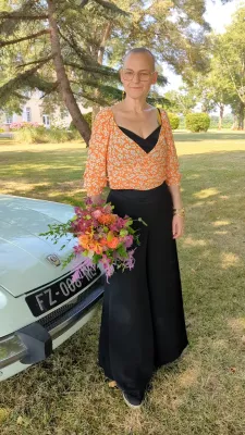 Sophisticated country-style bridal bouquet with orange and fuchsia roses and green foliage for a wedding in Savignac.