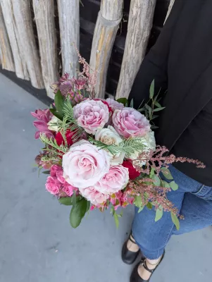 Sophisticated country-style bridal bouquet with pink, red, white roses, orchids, alstroemerias, and astilbes.