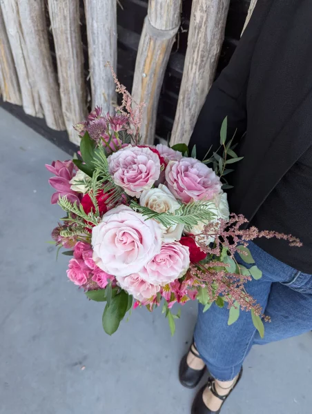 Sophisticated country-style bridal bouquet with pink, red, white roses, orchids, alstroemerias, and astilbes.