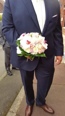 Bouquet de mariée rond style classique avec roses crème, roses poudrées, orchidées blanches et feuillage vert pour un mariage estival.