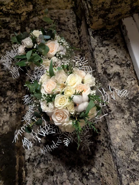 Magnifique bouquet de mariée classique avec roses blanches, roses pêche poudré, eucalyptus et boules de coton pour le mariage Lydie et William.