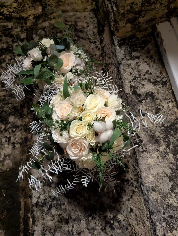 Magnifique bouquet de mariée classique avec roses blanches, roses pêche poudré, eucalyptus et boules de coton pour le mariage Lydie et William.