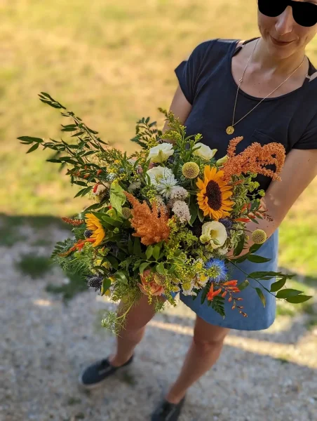 Magnifique bouquet de mariée champêtre avec tournesols, chardons et amarante pour un mariage estival.