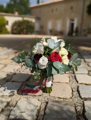 Bouquet de mariée champêtre éclatant avec roses blanches et rouges, alstroemeria et abondant feuillage d'eucalyptus pour un mariage d'été.