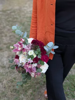 Bouquet de mariée bohème avec roses crème, bordeaux, orchidées roses et eucalyptus pour le mariage de Océane à Tabanac.