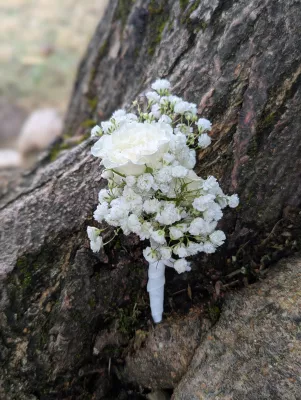 Sophisticated country-style buttonhole with gypsophila and small white rose for a wedding.