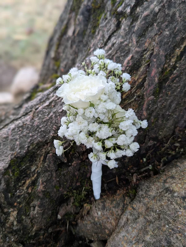Sophisticated country-style buttonhole with gypsophila and small white rose for a wedding.