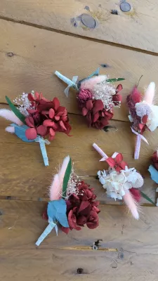 Assortment of sophisticated rustic buttonholes and floral bracelets with burgundy hydrangeas and pink pampas.