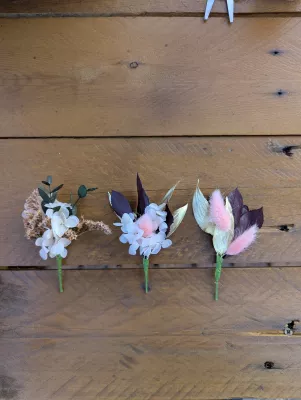 Three sophisticated rustic buttonholes with white hydrangeas, pink pampas grass, and gilded foliage for wedding.