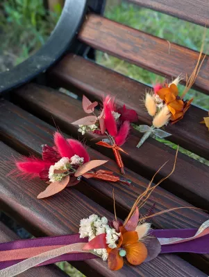 Boutonnières de mariage bohème et bracelet assorti avec fleurs séchées, lagurus rouge et mini orchidée orange.