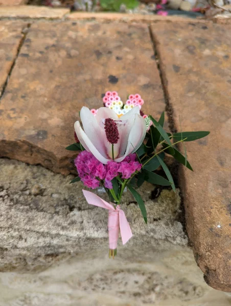 Boutonnière de mariage sur mesure avec une fleur de magnolia, de l'eucalyptus et une délicate fleur en perles artisanale.