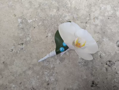 Minimalist buttonhole with a white orchid, a green leaf, and blue beads.